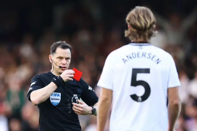 Referee Darren England gives a red card to Joachim Andersen