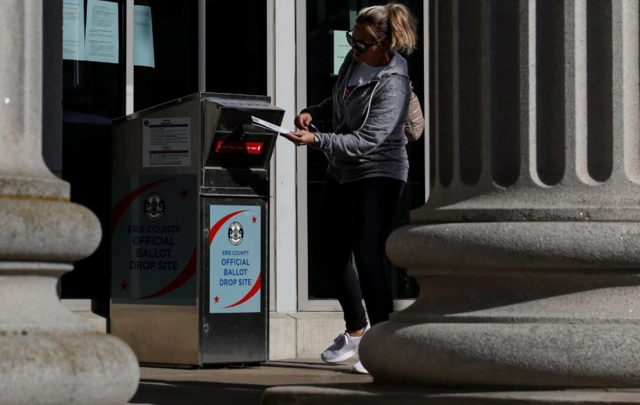 A woman drops off an election ballot at an Erie County ballot drop site in Erie, Pennsylvania