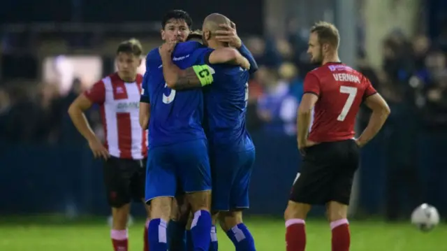 Lincoln City players look dejected as Chippenham Town celebrate their FA Cup win over the Imps in 2022