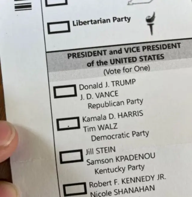 An image appearing to show a ballot paper where the box for Kamala Harris has a very small black dot inside, which the other candidates do not have