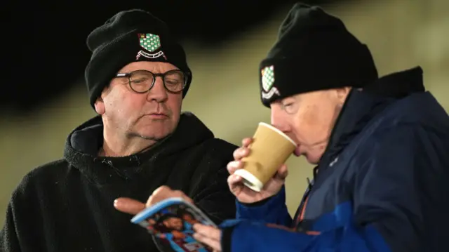 Chesham United fans read the matchday programme