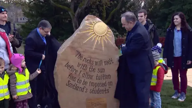 Alex Salmond and children unveil a rock with the quotation "The rocks will melt with the sun before I allow tuition fees to be imposed on Scotland's students'