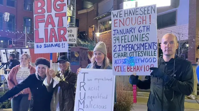 Anti-Trump protesters hold signs opposing him