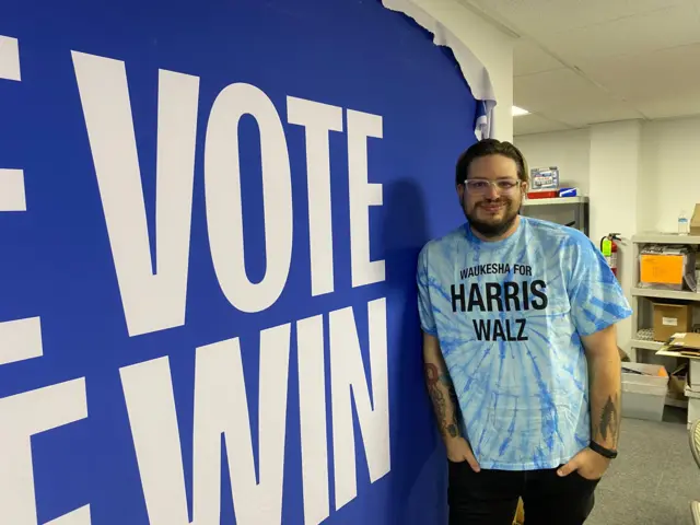 Matt Mareno in an office leaning against a vote poster