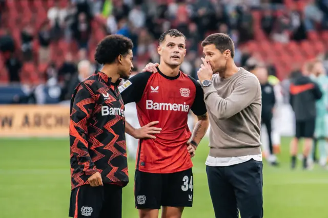 Alonso chats to Xhaka and Adli on the pitch post Frankfurt