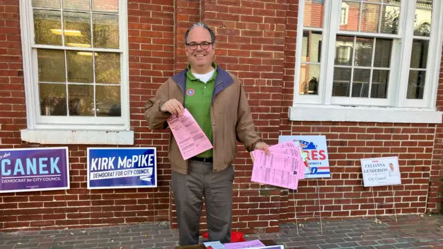 A Republican volunteers with sample ballots in Alexandria, Virginia