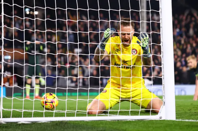 Brentford goalkeeper Flekken holds his head in his hands with the ball in his net