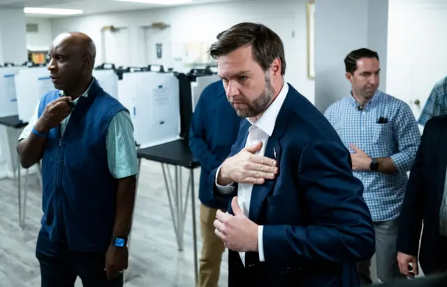 Vance walks with his hand on his heart in a polling station in Ohio