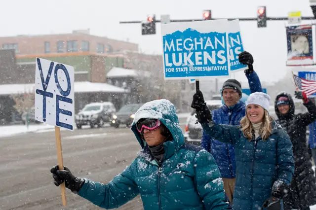 Voters wave signs in Steamboat Springs, Colorado encouraging people to vote for Kamala Harris