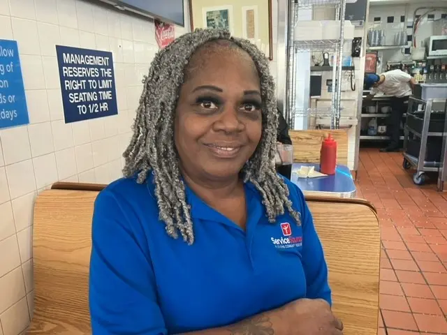 Patricia sitting in a diner wearing a blue shirt