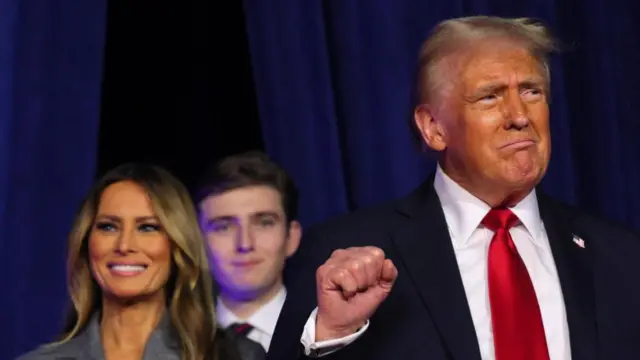 Republican presidential nominee and former U.S. President Donald Trump makes a fist as he takes the stage with his wife Melania and son Barron to address supporters at his rally, at the Palm Beach County Convention Center in West Palm Beach, Florida, U.S., November 6, 2024.