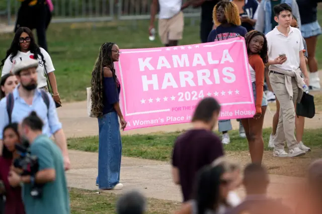 Two women hold a Kamala Harris 2024 sign