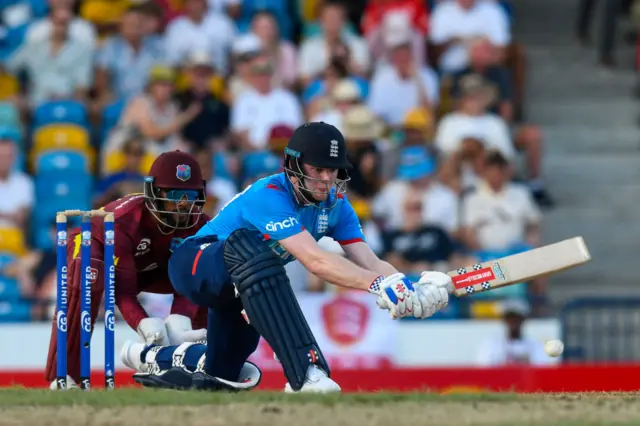 Dan Mousley of England hits four as Shai Hope of the West Indies looks on