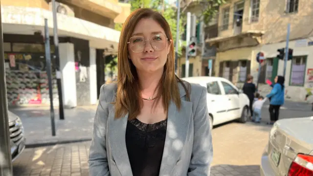 Sanaa El Banj standing in a street, wearing a grey jacket