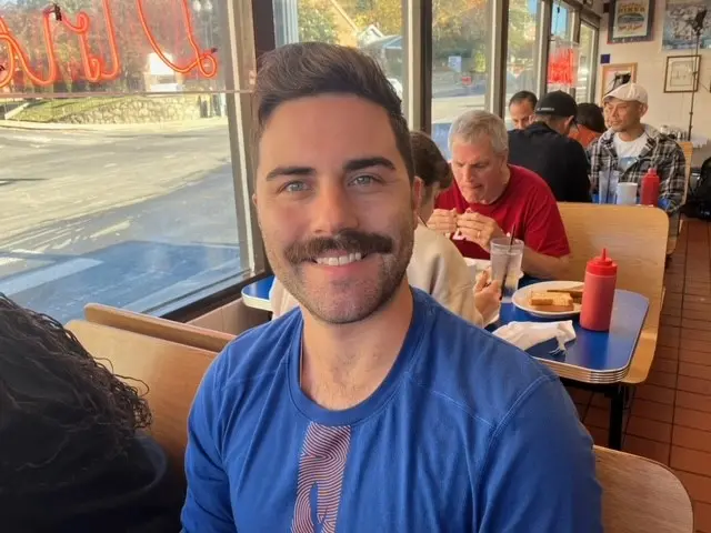 Colby Wood sitting in a diner wearing a blue T-shirt