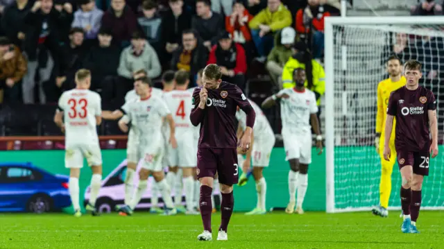 Hearts' Stephen Kingsley looks dejected as Heidenheim's Sirlord Conteh celebrates scoring to make it 1-0 with teammates