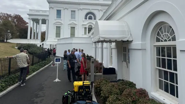 A line of journalists stand outside the White House