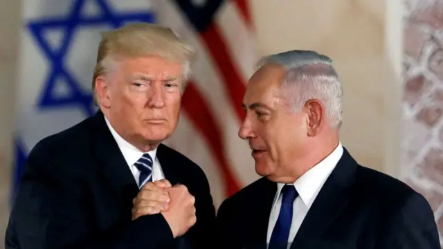 Donald Trump in black suit and matching tie with light blue stripes shakes hands with Benjamin Netanyahum, also in black suit and blue tie, after a speech in Jerusalem in 2017