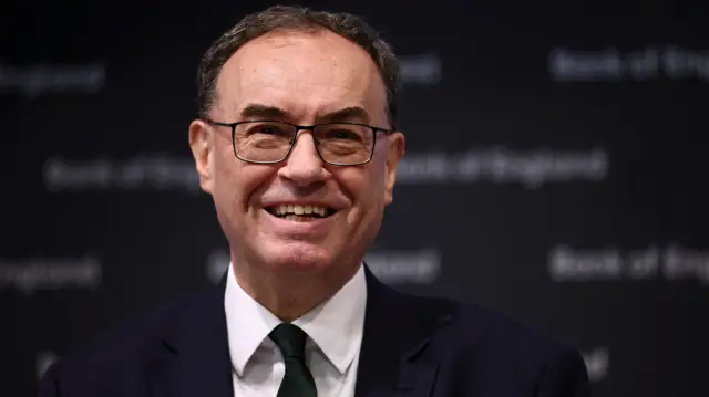 Andrew Bailey, smiling while wearing a dark suit and black tie