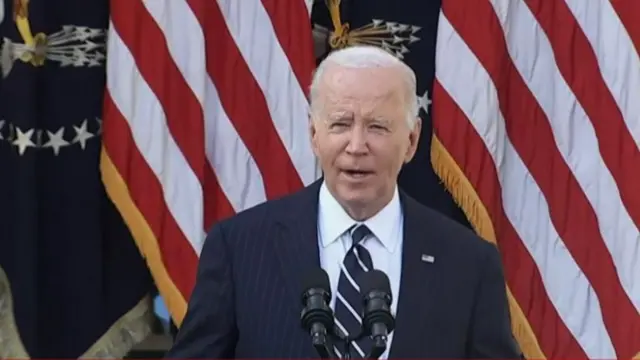 Biden speaks in the Rose Garden at the White House in front of an American flag