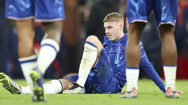 Cole Palmer sitting on the field after Chelsea play Manchester United