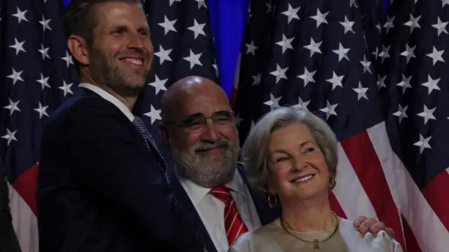 LaCivita grins, his hand on Wiles's shoulder and they stand in front of American flags