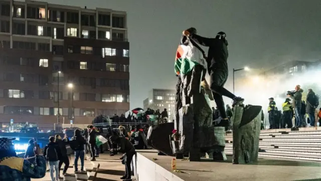 A protester wraps a Palestinian flag around a statue at Amsterdam's Anton de Komplein square