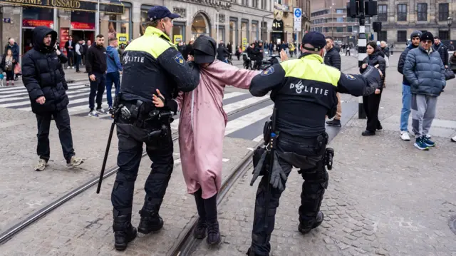 Two police officers carrying a man in a square