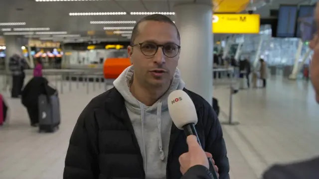 A man speaking into a microphone at an airport