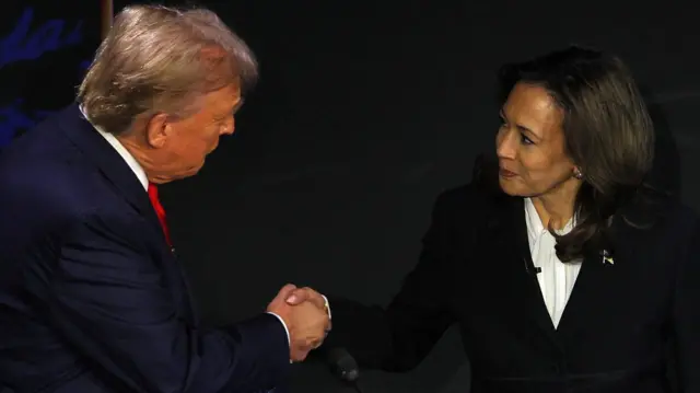 Donald Trump and Kamala Harris shake hands on stage during a TV debate