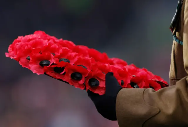 Poppy wreath is held by a member of the armed forces