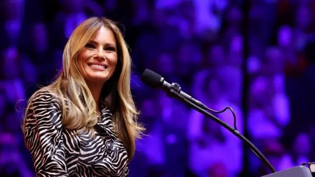 Melania Trump on stage at Madison Square Garden. She smiles next to a microphone