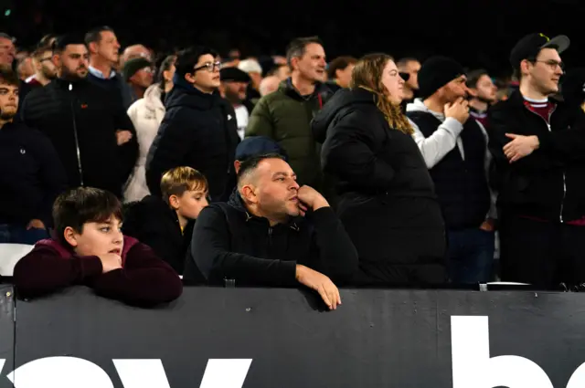 West Ham fans look on from the stands with glum expressions on their faces