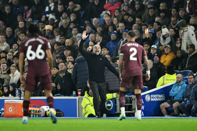 Guardiola waves instructions to his players from the touchline