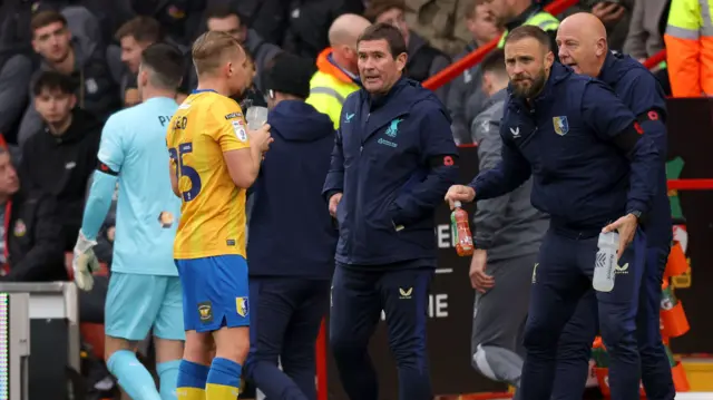 Mansfield manager Nigel Clough talks to midfielder Louis Reed