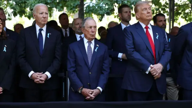 Biden, New York Mayor Michael Bloomberg, and Trump stand in a row clasping their hands together and holding them in front of themselves