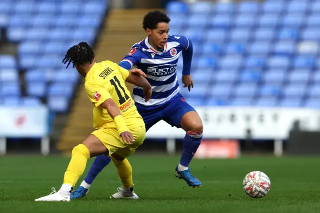 Ben Starkie of Harborough Town is challenged by Ben Elliot of Reading