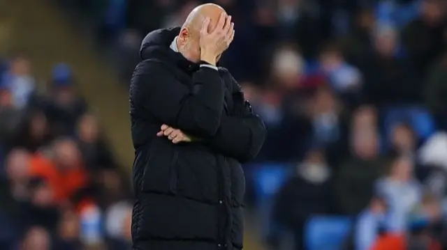 Pep Guardiola holds his head on the touchline