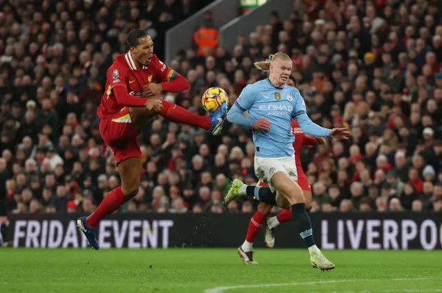 Virgil van Dijk challenges with Erling Haaland.