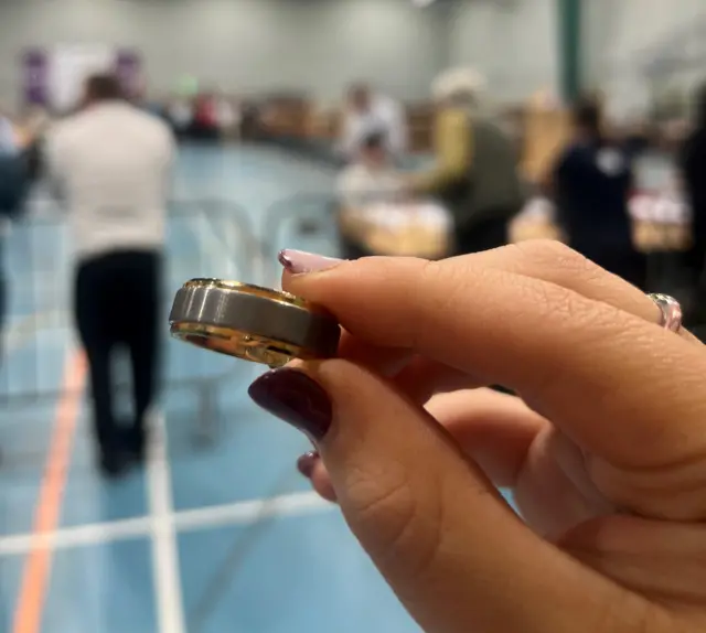 Close up of a woman's hand holding a silver and gold wedding ring