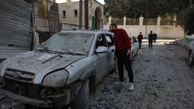 A man inspects the interior of a damaged car