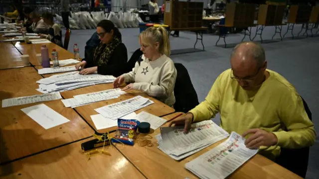 Three vote counters look over ballot papers