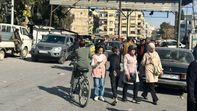 People walk about and cars block the roads in Damascus