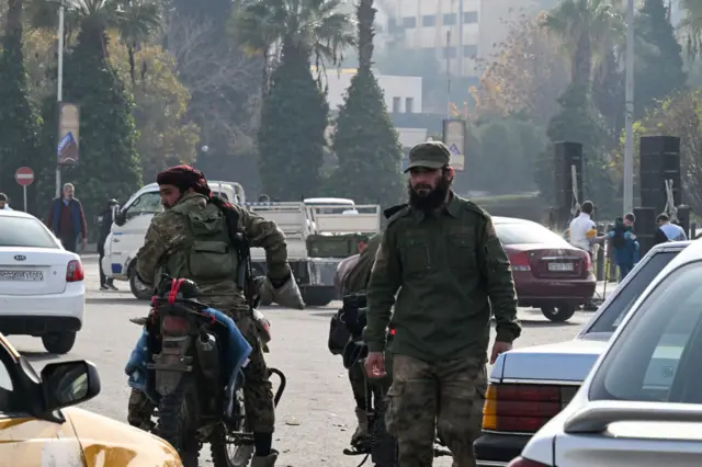 Rebel fighters patrol a street in Damascus on December 10