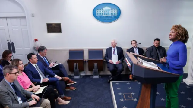 Reporters and officials speak in the White House briefing room