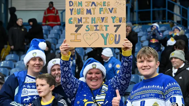 Leeds fans at Elland Road wearing Christmas jumpers and holding up a sign for Dan James