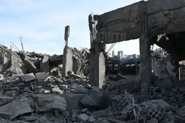 A destroyed building, little is left standing and much rubble is on the ground