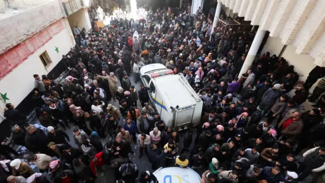 People gather as members of the Syrian civil defence group, known as the White Helmets, search for prisoners underground at Sednaya prison