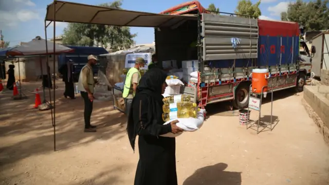 People receive food baskets provided by the WFP at a camp of Internally Displaced People (IDP) at Ma'arrat Misrin, Idlib, northwest Syria, 14 October 2024