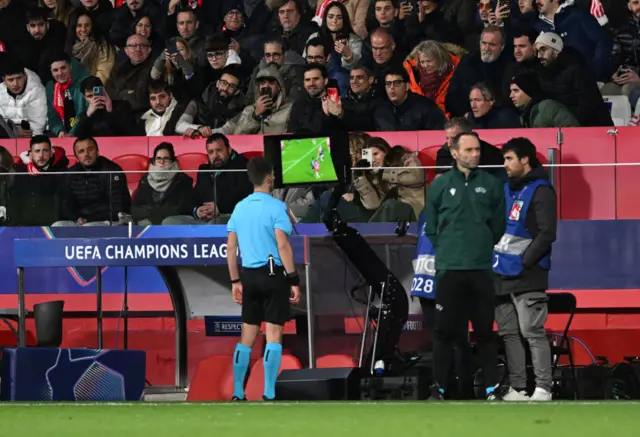 Referee Benoit Bastien reviews the VAR monitor